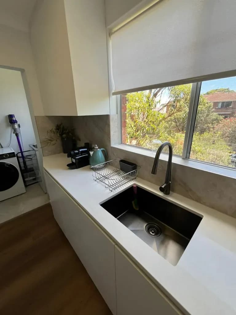 A kitchen after an Orison clean: clear stone benchtop and a spotless black sink