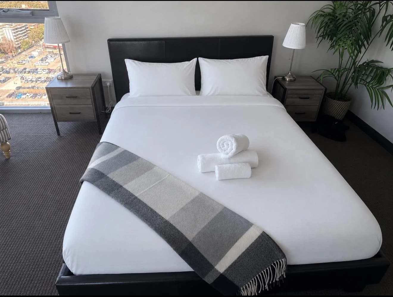 A staged bed with pressed white linen and rolled towels after an Orison turnover
