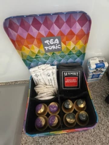 A stocked amenity kit with tea, coffee pods, and milk laid out for guests